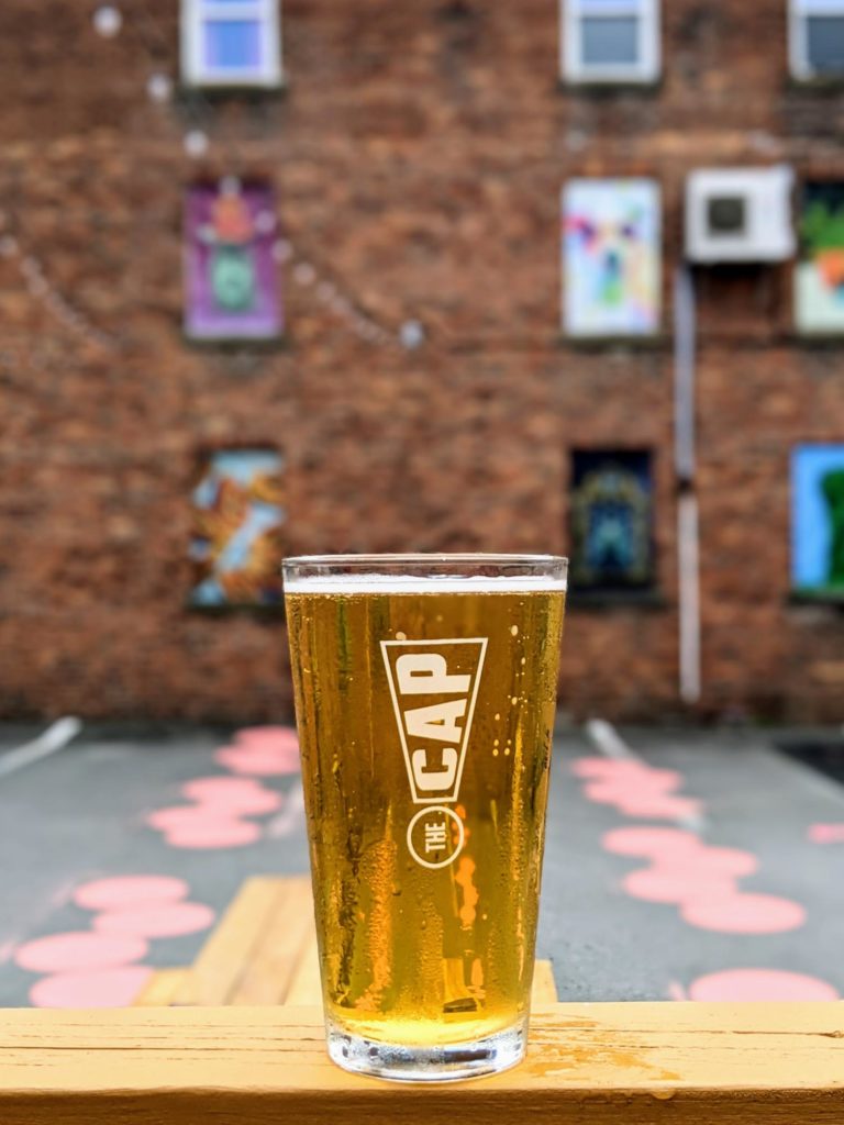 The Capital Fredericton, pint on ledge with brick wall behind it