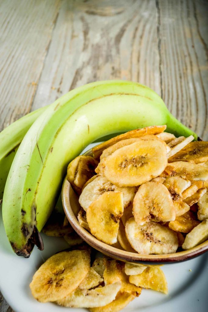 Dried bananas plantains with fresh bananas, wooden background copy space