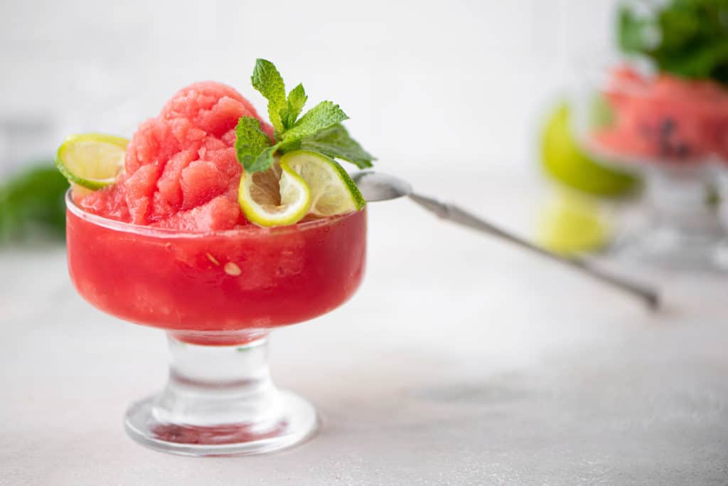 Watermelon cremolada in a clear glass garnished with mint and lime