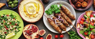 Assorted Middle Eastern and arabic dishes on a dark rustic background, border. Hummus,tabbouleh, salad Fattoush,pita,meat kebab,falafel,baklava,pomegranate. Halal food.Top view, flat lay, copy space.