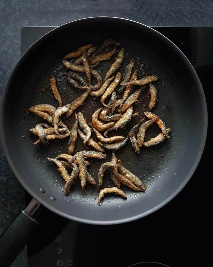 Paistetut Muikut Fried Vendace Finnish food on black frying pan and black background