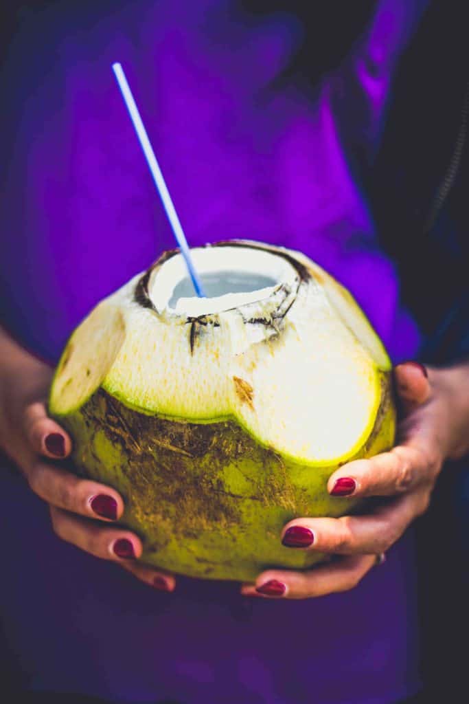 Drinks in Brazil Agua de Coco in someone's hands with a purple shirt