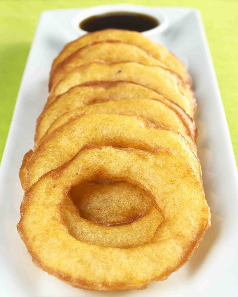 Popular Peruvian dessert called Picarones made from squash and sweet potato and served with Chancaca syrup (kind of honey) which is the black sauce in the back (Selective Focus Focus on the upper part of the first ring)