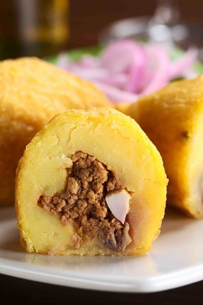 Peruvian dish called Papa Rellena (Stuffed Potato) made of mashed potatoes and filled with meat and egg (Selective Focus Focus on the front of the half papa rellena)