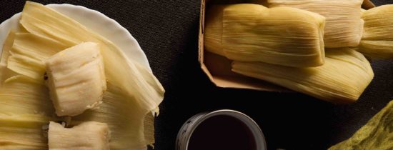 Typical Peruvian dish, corn cake, wrapped in corn husks, exposed on a dark background.