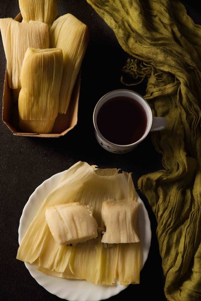 Peruvian snacks humitas Typical Peruvian dish, corn cake, wrapped in corn husks, exposed on a dark background.