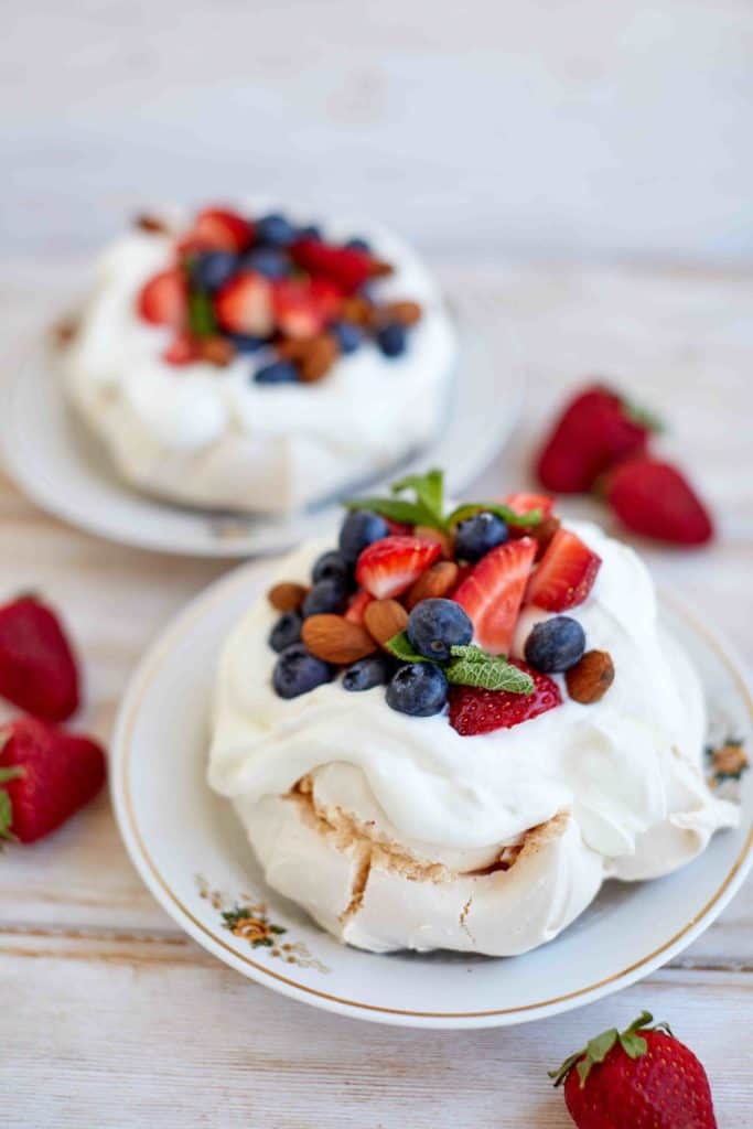 Two white merengón Colombia desserts similar to pavlova with berries on top.