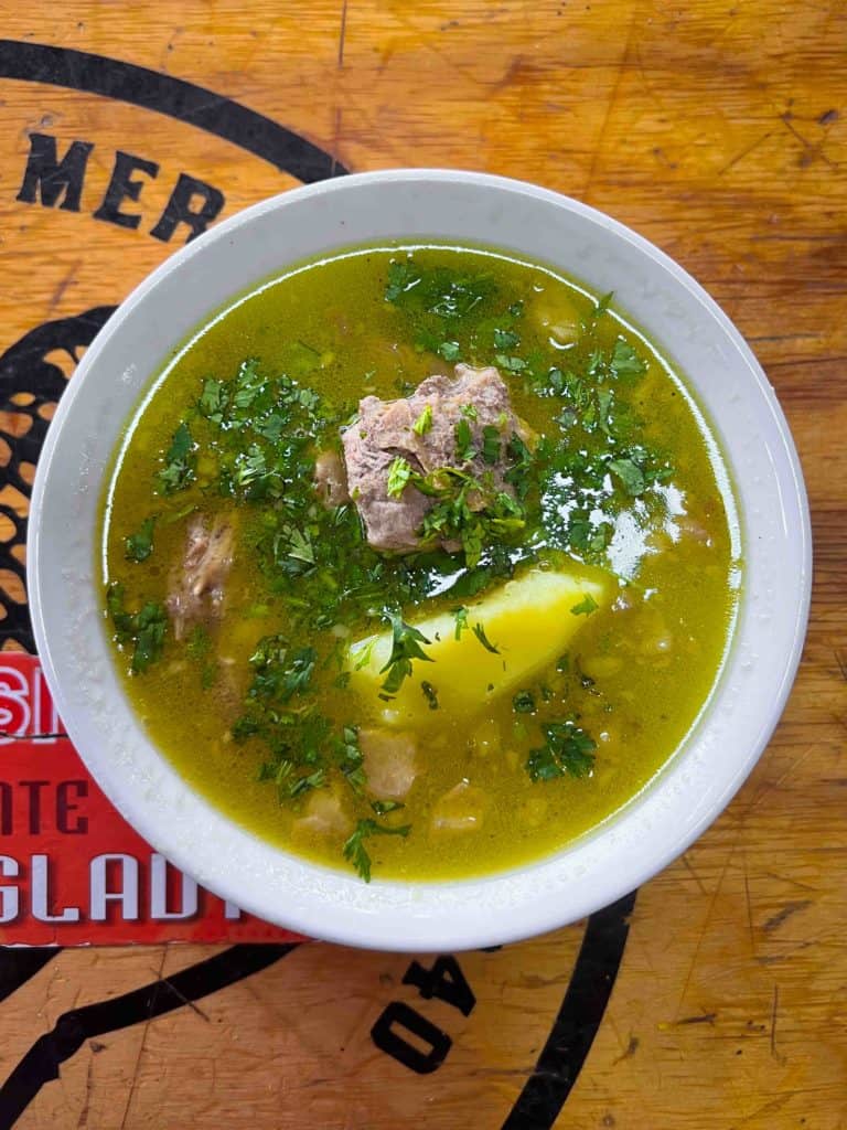 Costilla de res soup in white bowl on wooden table