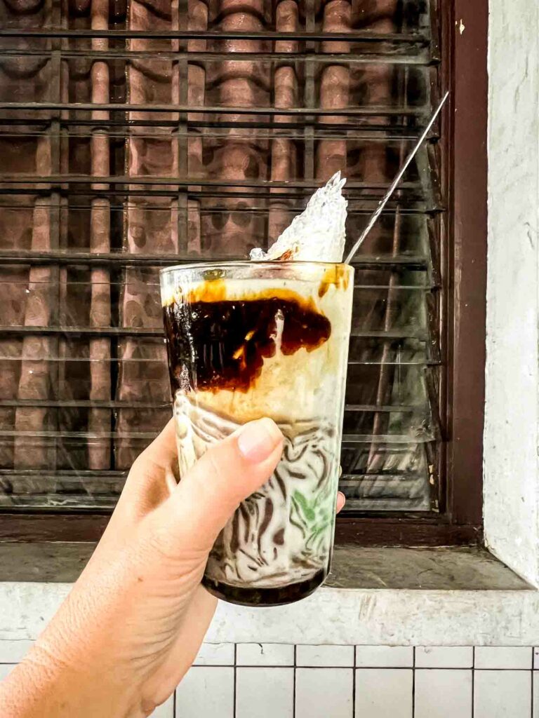 Indonesian drink es cendol in a woman's hand against the background of a window