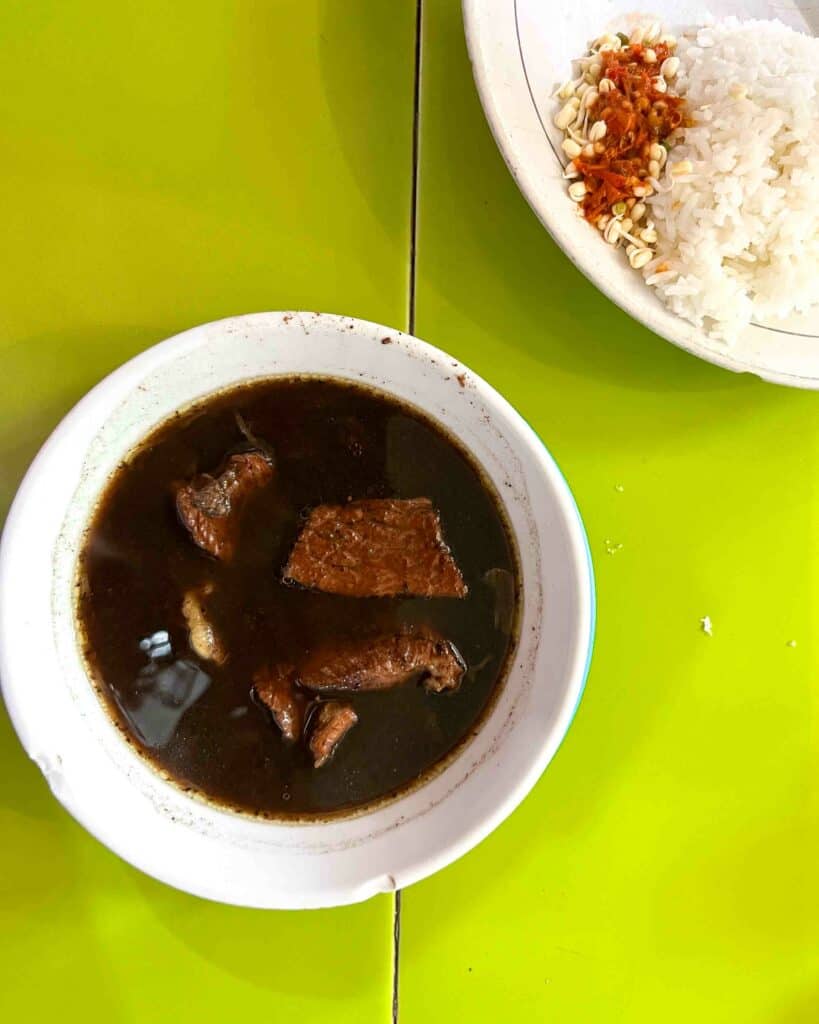 rawon a traditiona surabaya food on table with bean sprouts sambal and rice