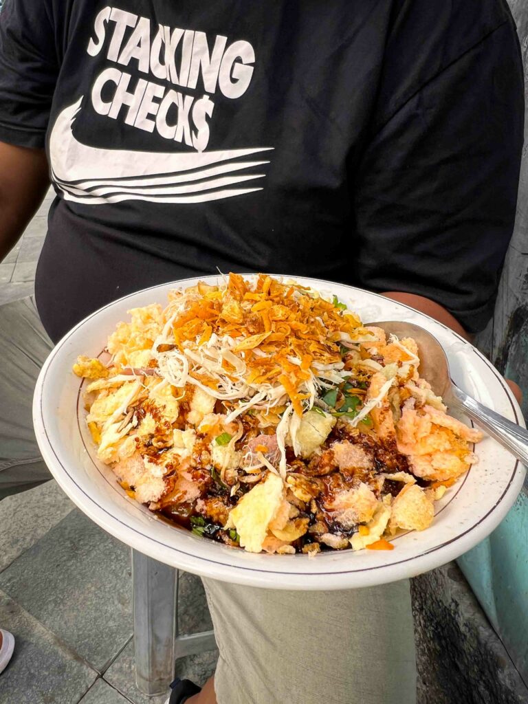 man holding bubur ayam on a plate in Jakarta