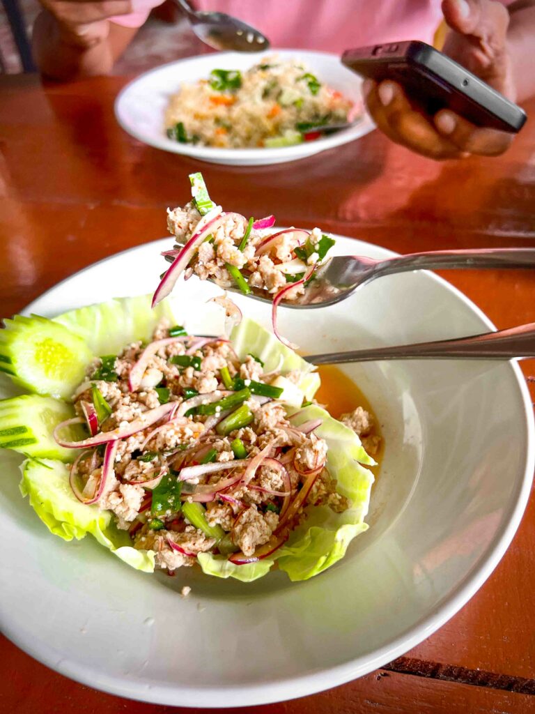 larb moo also known as thai pork salad on a white plate dark table in a Thai restaurant