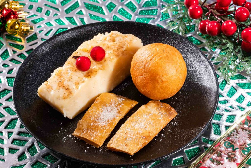 Christmas foods in Colombia on a black plate" Buñuelos, natilla and hojuelas, Colombian cuisine - Christmas tradition
