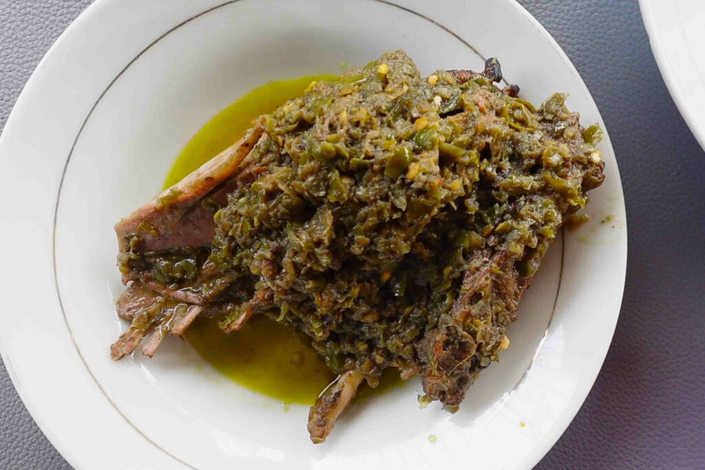 Green chili sauce on duck on a white plate a typical Padang food called sambal lado mudo