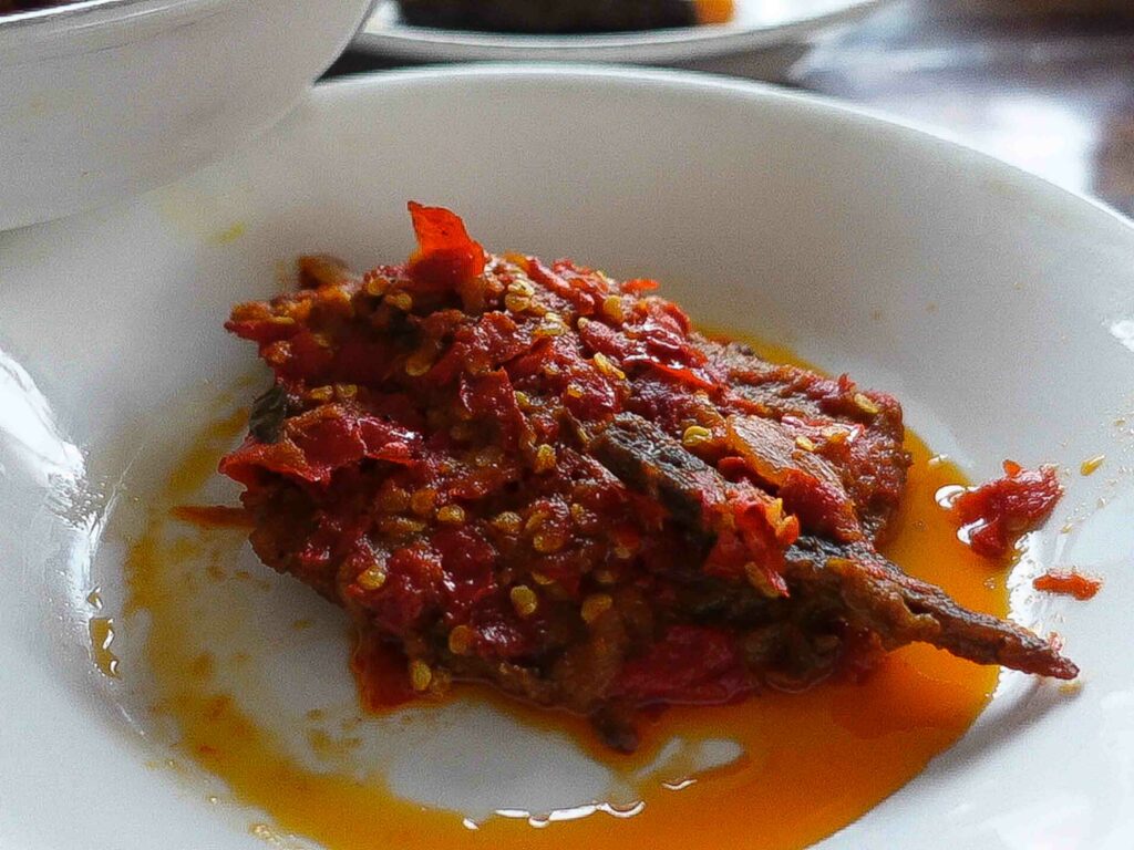 Dendeng balado is a spicy Padang food made from crispy beef dish. Thin slices of beef are marinated, then dried and fried until they achieve a chewy, jerky-like texture. Featured in a white bowl