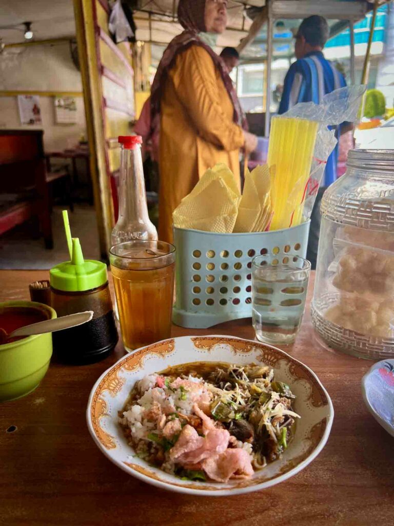 Soto Padang a beef noodle soup with rice in a bowl in Indonesian restaurant