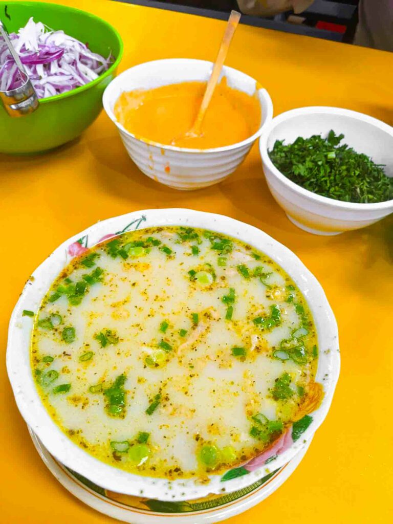 caldo de cabeza de mocho a traditional Ecuador soup in the market in Cuenca served with green onion, red onion and aji hot sauce