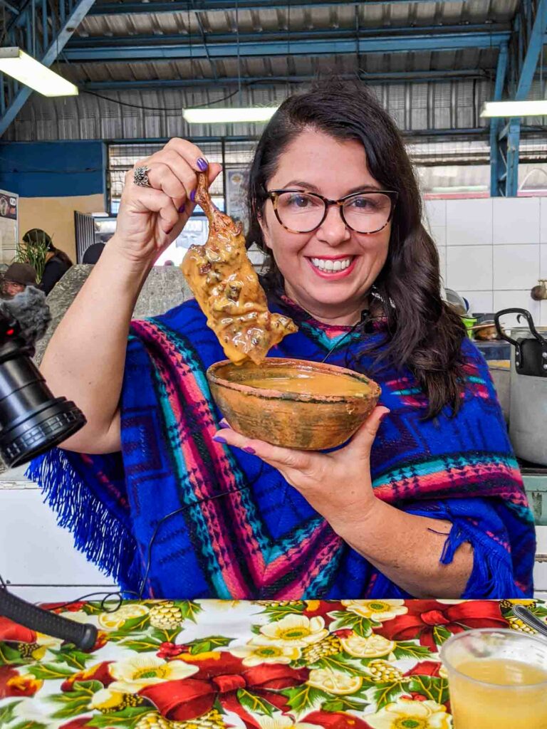 Ayngelina holding colada de cuy, a traditional Ecuador soup in Cotacachi made with cuy dipped into the soup