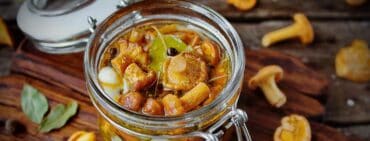 pickled chanterelles in jar on a rustic cutting board