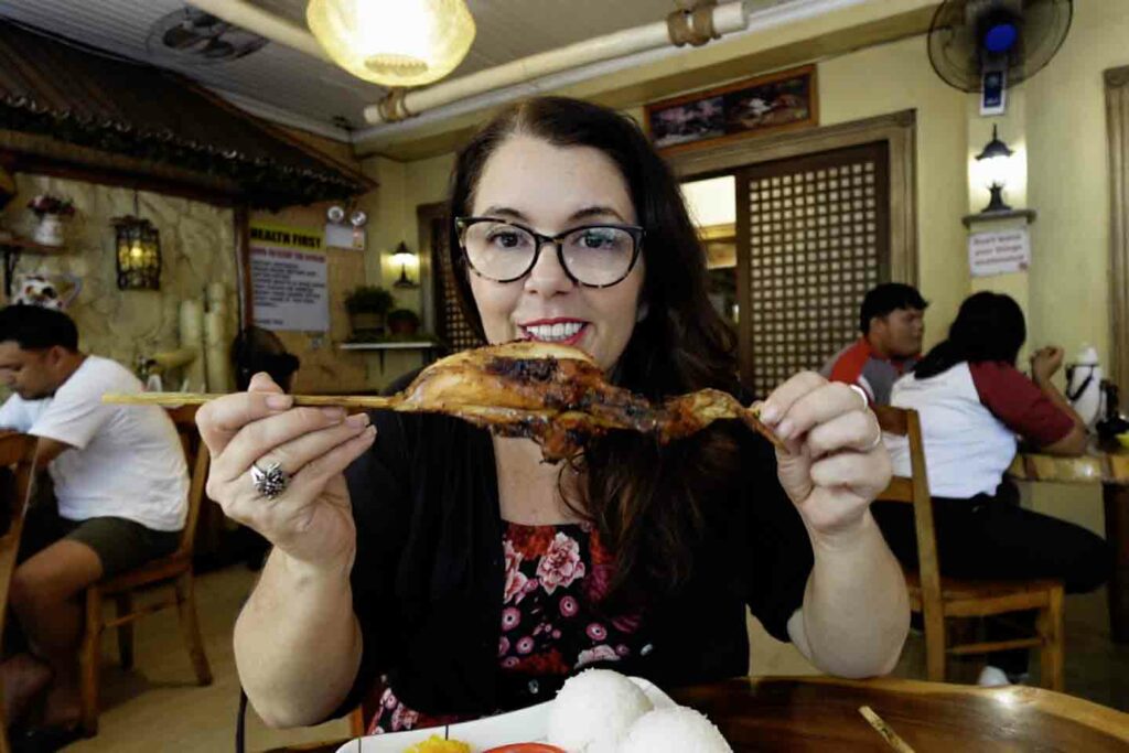 Woman showing chicken inato on skewer at Jo's Inato in Dumaguete Philippines