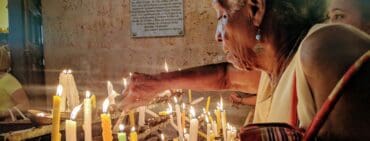 Woman lighting candles during Christmas in Cuba at a church in Havana