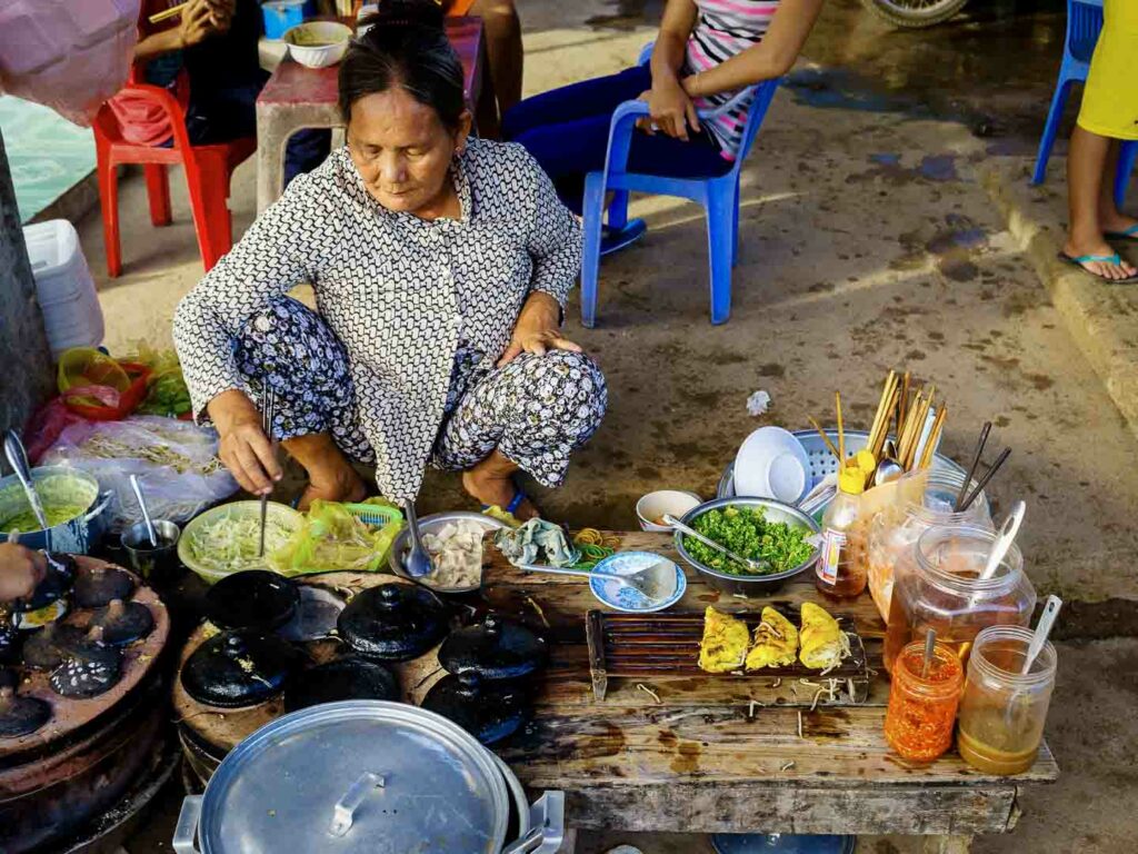 Vietnamese woman cooking banh xeo at market
