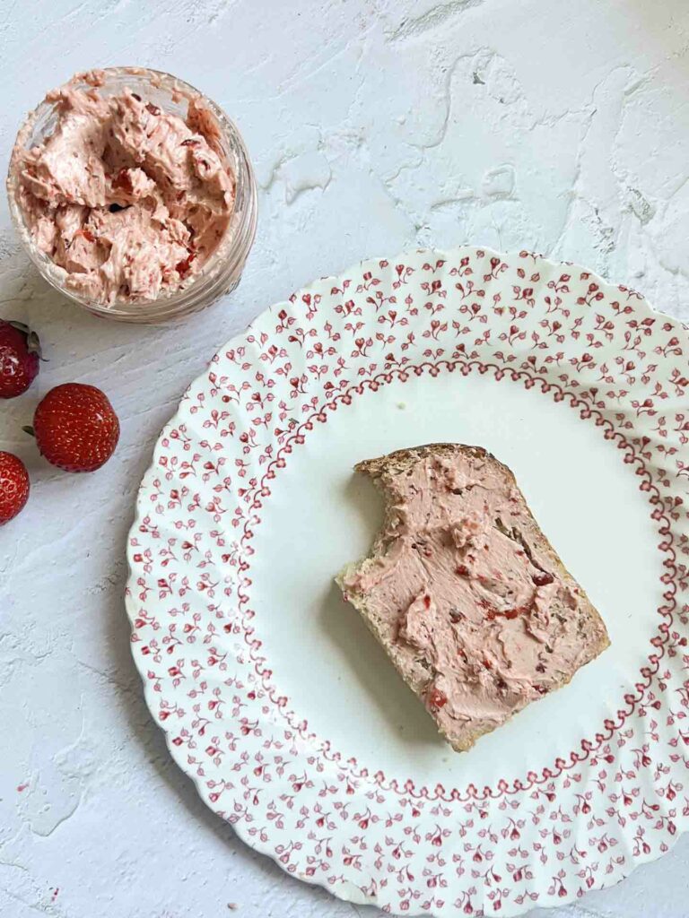 whipped strawberry chipotle butter in a jar next to a piece of bread with it on a plate