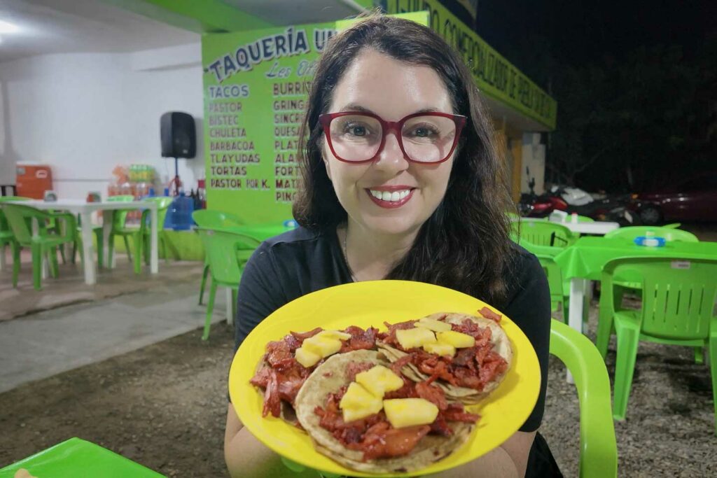 Ayngelina holding yellow plate of tacos al pastor at Taqueria Uno y Mas in Puerto Escondido