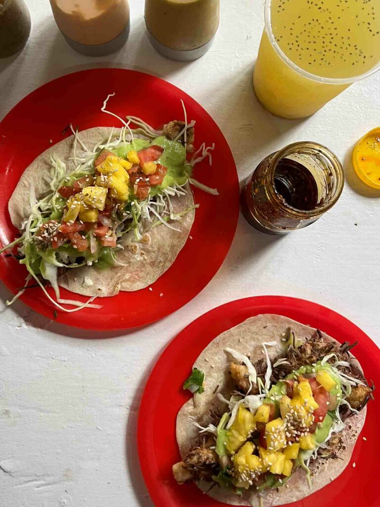 Pepe's Tacos, coconut fish and shrimp taco on table with drink and condiments in Puerto Escondido