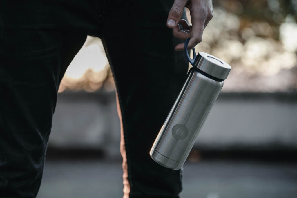 man holding reusable water bottle walking down the street