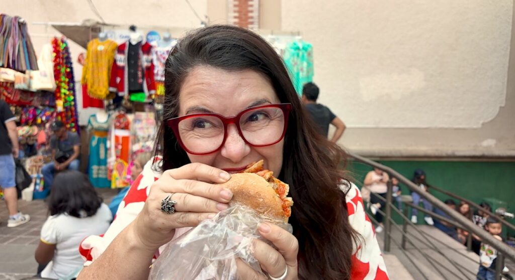 Ayngelina eating guacamaya a traditional food in Guanajuato with chicharron on a bolillo roll