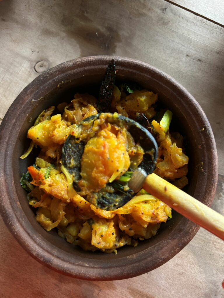 Bowl of Ala Theldala Sri Lanka Deviled Potatoes with a spoon raising some of the potato closer to the camera