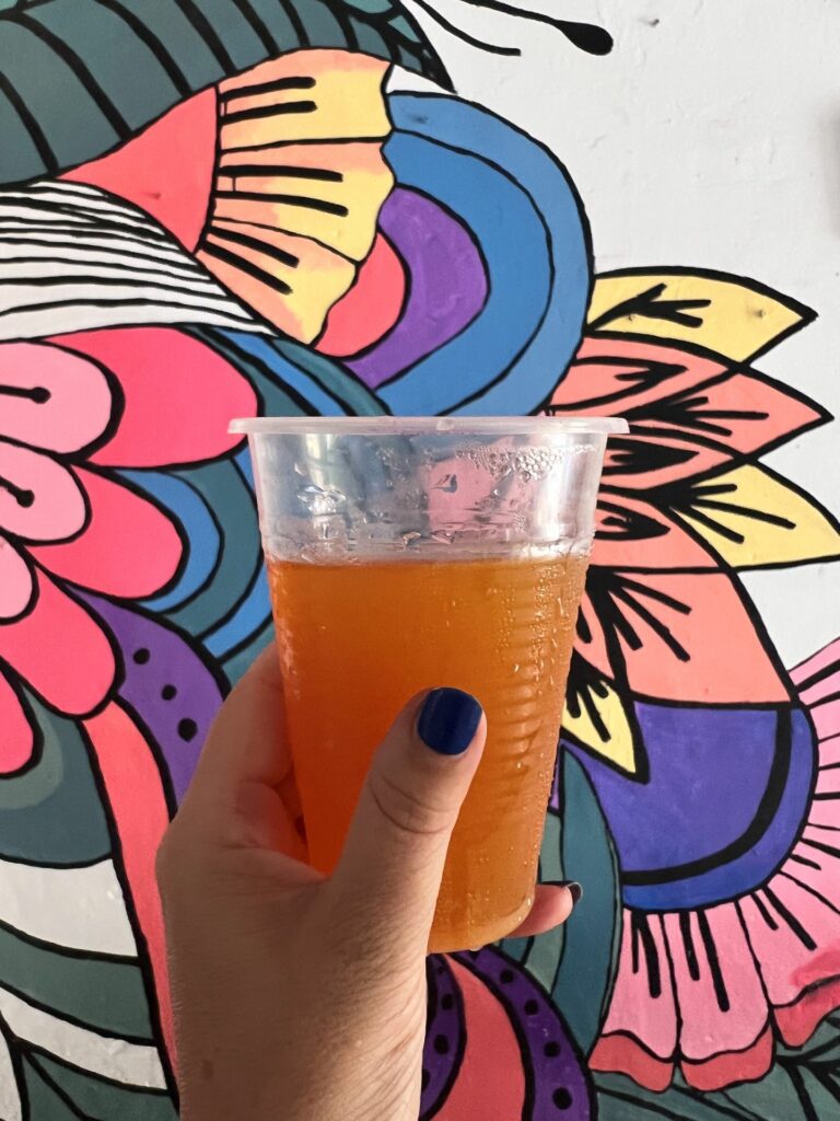 aguapanela in woman's hand with colorful artwork in background in Santa Marta Colombia