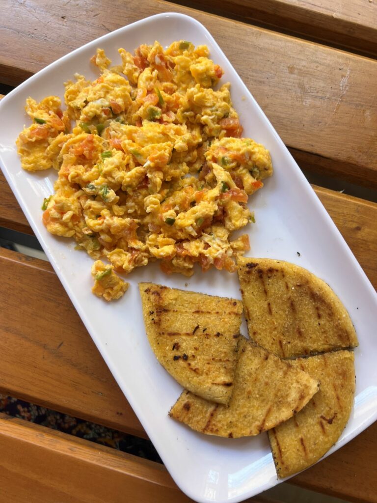 huevos pericos and arepitas of green banana on a white plate at a restaurant, a common food for breakfast in Santa Marta Colombia