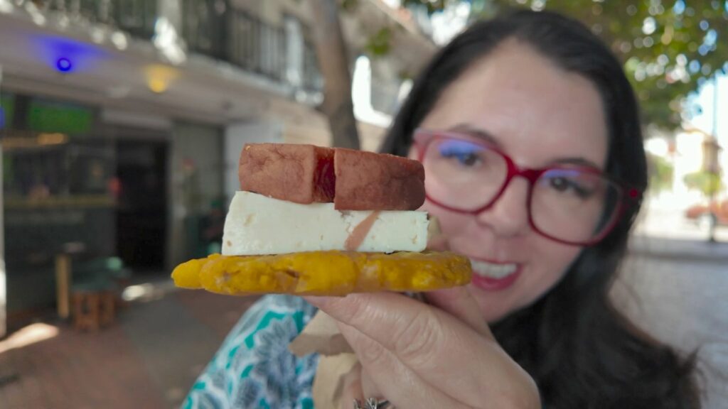 Ayngelina holding a traditional Cartagena snack, patacones with queso costeno and salchicha from a famous kiosk