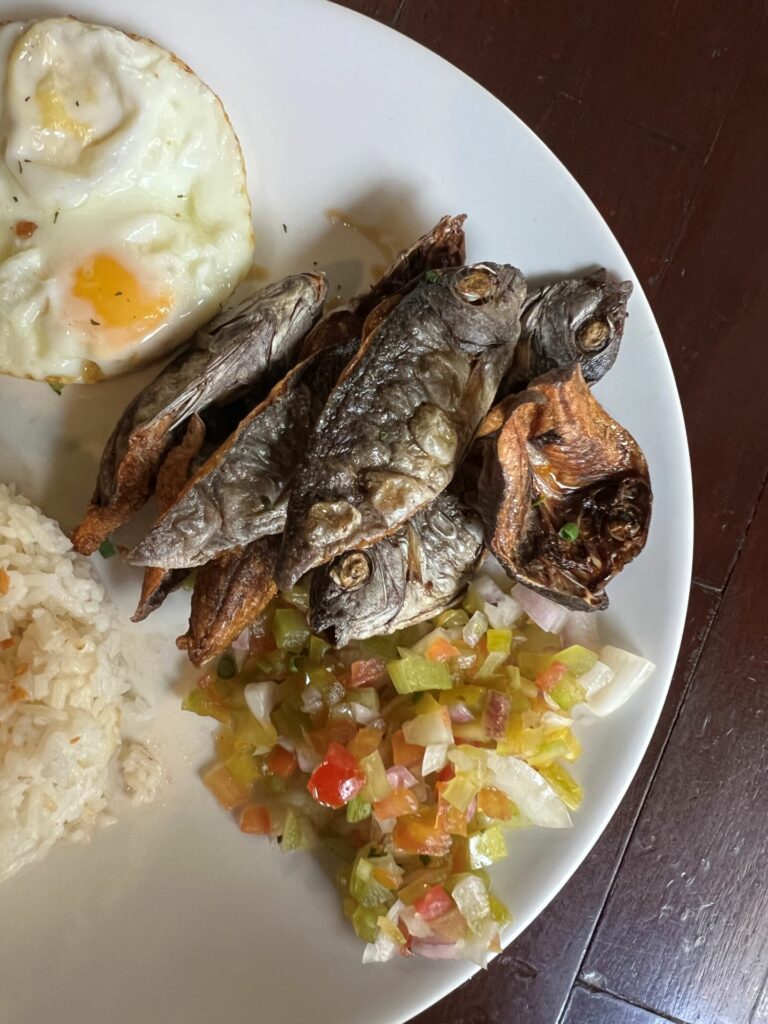 Fried fish served with tangy pickled vegetables and a sunny-side-up egg, showcasing Palawan's authen.