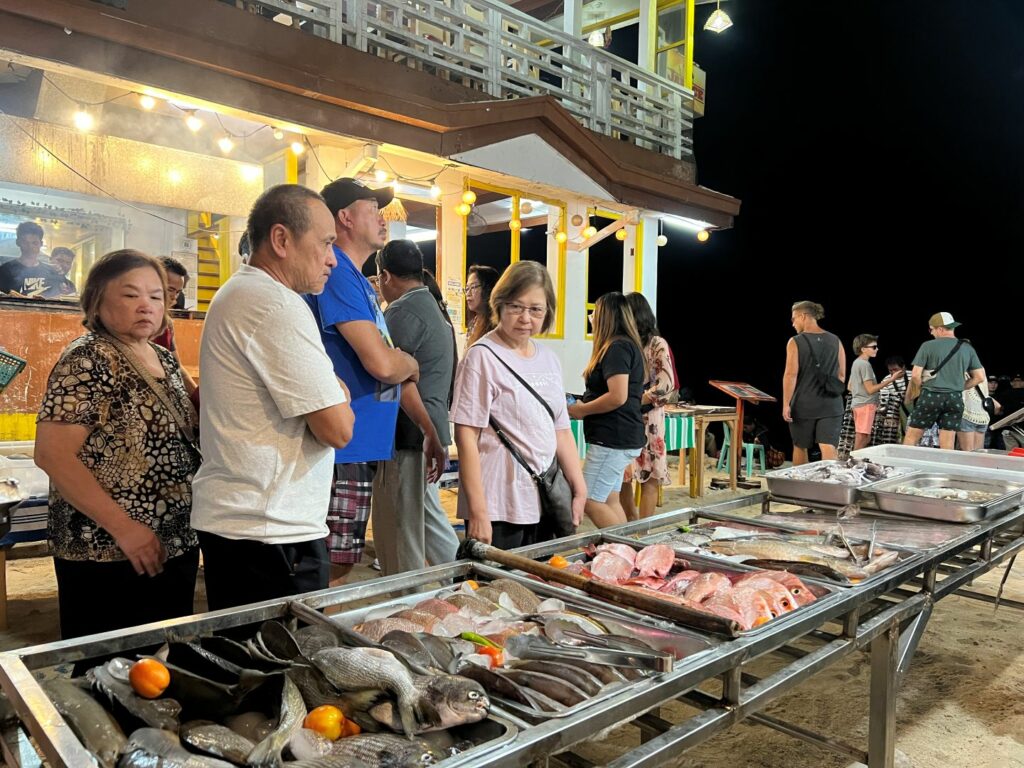 People looking at seafood in streets of El Nido. Uncooked you pick the fish and the restaurant will cook it for you.