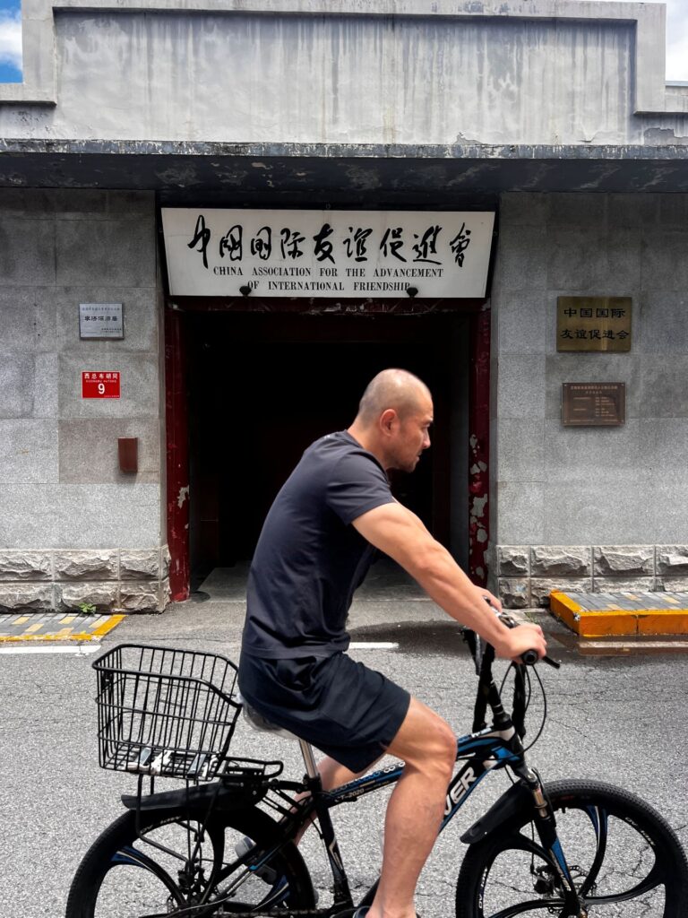 men riding bike in China outside building for international friendships