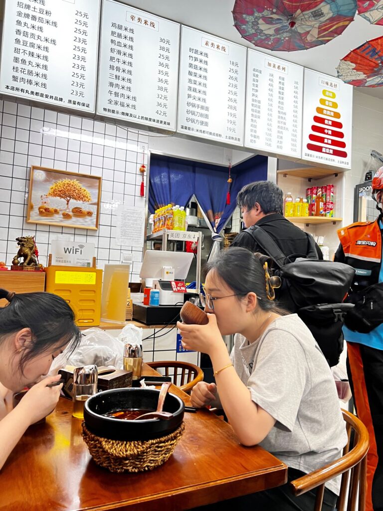 Beijing noodle restaurant with guests eating and menu in back